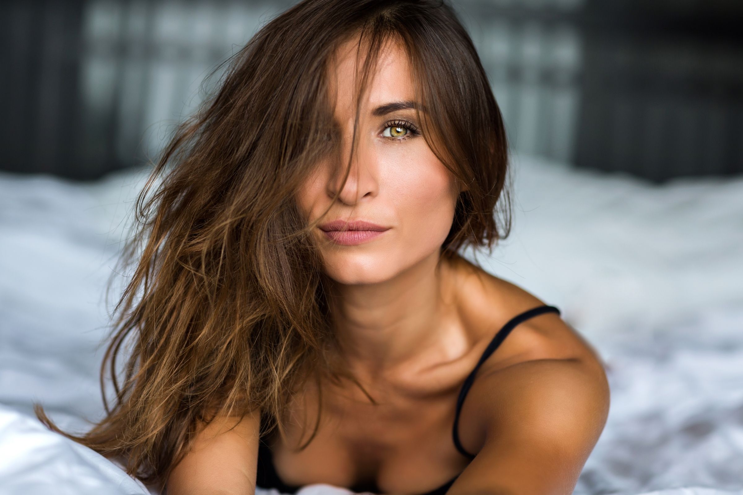 Brunette woman in black lingerie posed in a bright bedroom